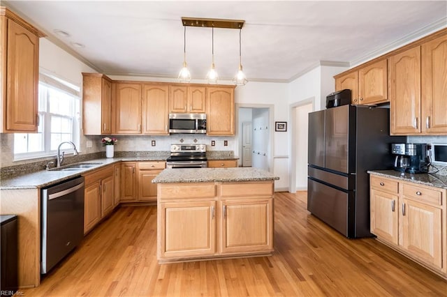 kitchen featuring crown molding, stainless steel appliances, a sink, a kitchen island, and light wood-type flooring