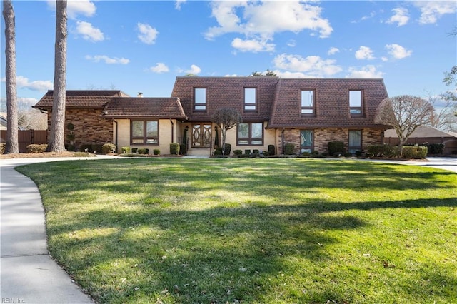 view of front of house with brick siding, fence, a front lawn, and mansard roof