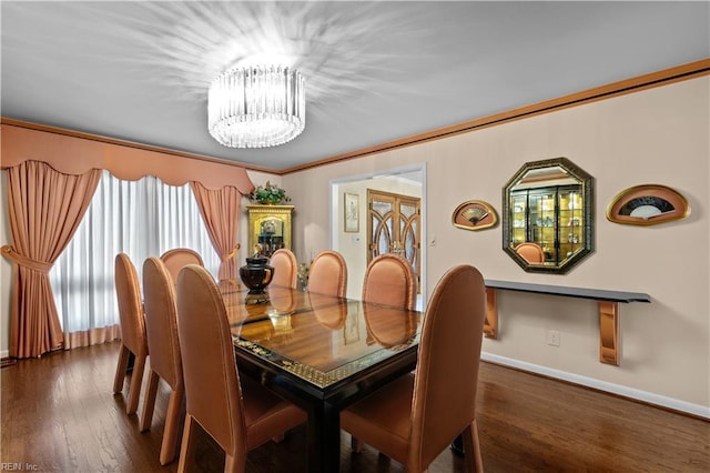 dining space featuring baseboards, a chandelier, wood finished floors, and crown molding