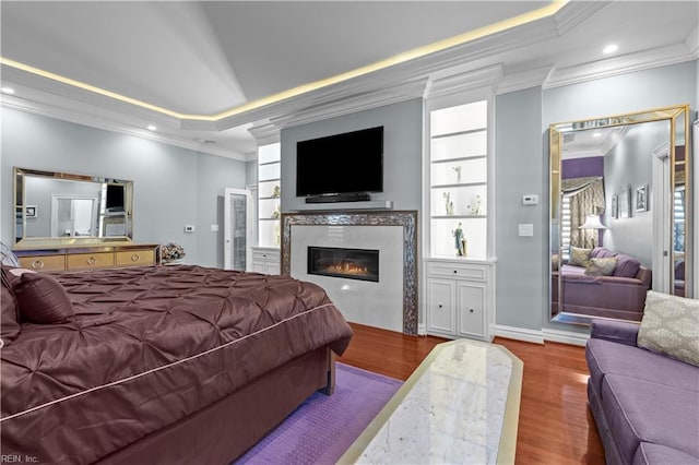 bedroom with a glass covered fireplace, crown molding, and wood finished floors