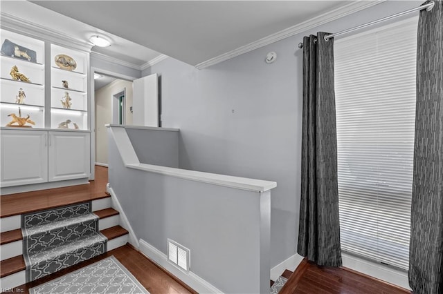 staircase featuring baseboards, wood finished floors, visible vents, and crown molding