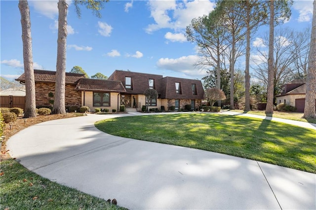 view of front of home featuring curved driveway, mansard roof, and a front yard