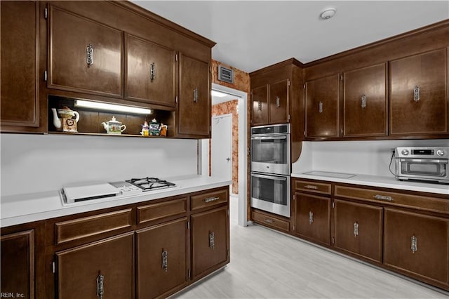 kitchen with open shelves, light countertops, visible vents, stainless steel double oven, and dark brown cabinetry