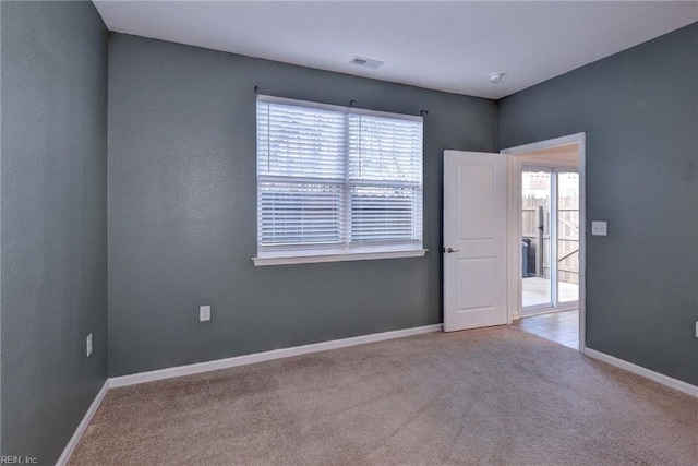 unfurnished room with visible vents, baseboards, and light colored carpet