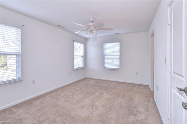 unfurnished room featuring a ceiling fan, a healthy amount of sunlight, light carpet, and baseboards