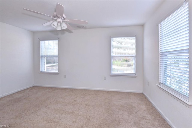 unfurnished room with a healthy amount of sunlight, light carpet, and baseboards