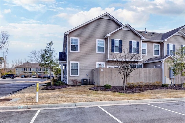 townhome / multi-family property with uncovered parking, fence, and central air condition unit