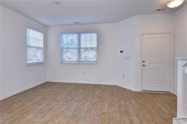 unfurnished room featuring baseboards, visible vents, and light wood-style floors