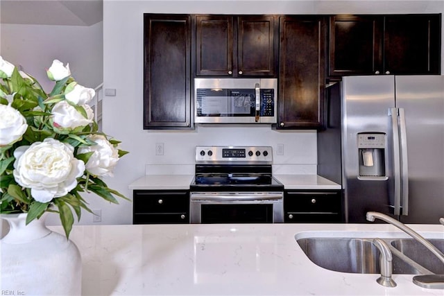 kitchen with dark brown cabinetry, appliances with stainless steel finishes, and a sink