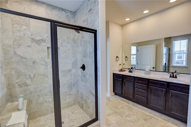 bathroom with a stall shower, a healthy amount of sunlight, a sink, and double vanity