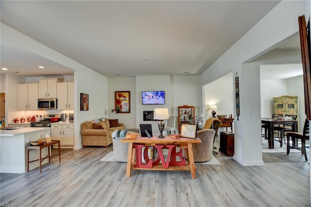 living area with light wood-style flooring, baseboards, and recessed lighting