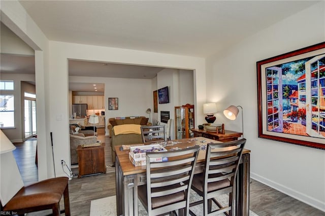 dining space with baseboards and wood finished floors