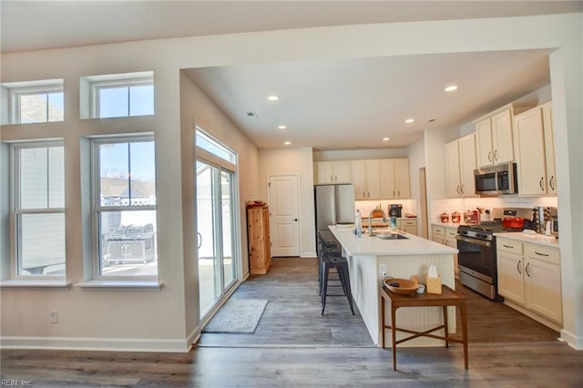 kitchen with a breakfast bar, tasteful backsplash, appliances with stainless steel finishes, a sink, and baseboards