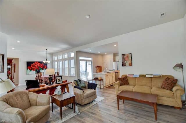 living area featuring an inviting chandelier, light wood-style flooring, visible vents, and recessed lighting