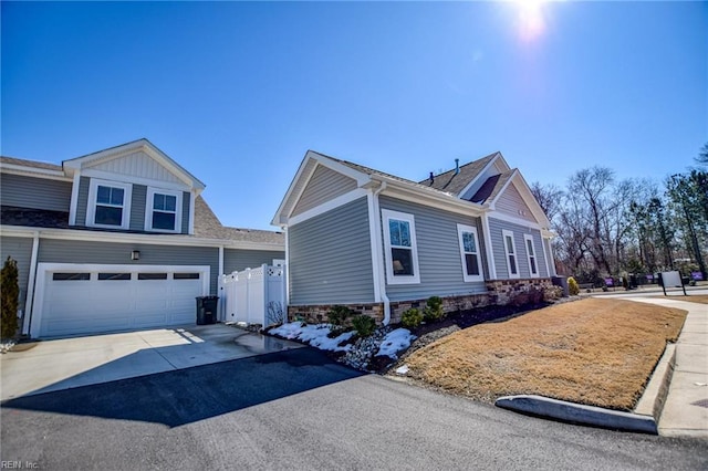 view of front facade featuring driveway, an attached garage, and fence