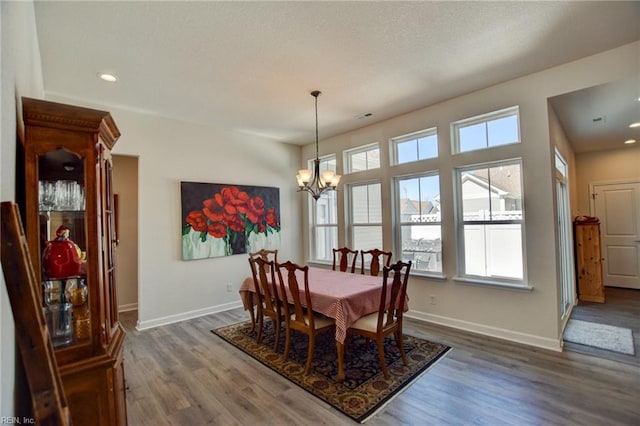 dining space featuring baseboards, a healthy amount of sunlight, an inviting chandelier, and wood finished floors