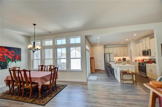 dining area featuring light wood-style floors, baseboards, a chandelier, and recessed lighting