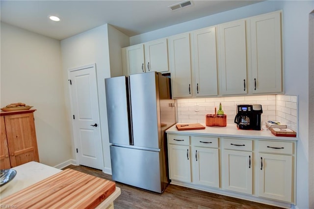 kitchen with tasteful backsplash, freestanding refrigerator, white cabinets, and visible vents