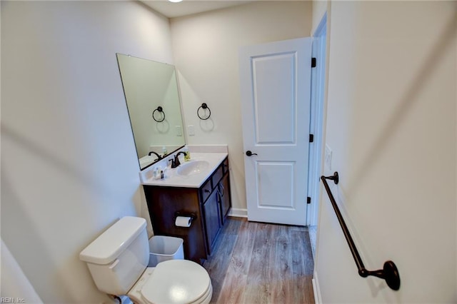 half bathroom featuring vanity, toilet, and wood finished floors