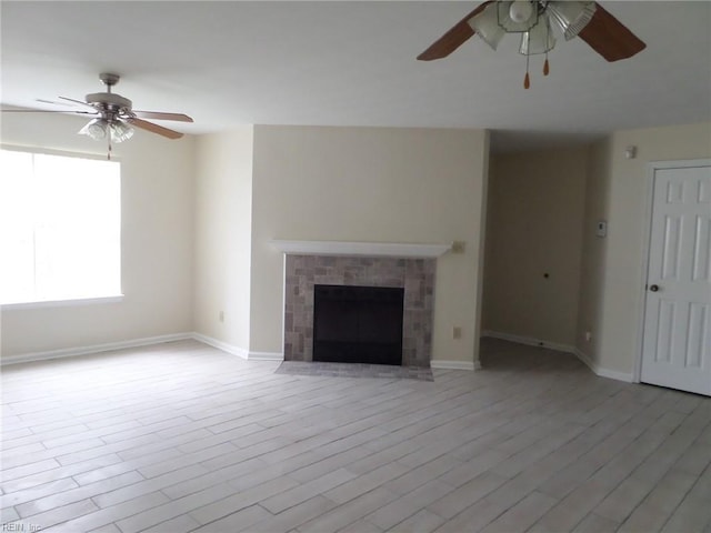 unfurnished living room featuring a ceiling fan, baseboards, wood finished floors, and a tile fireplace