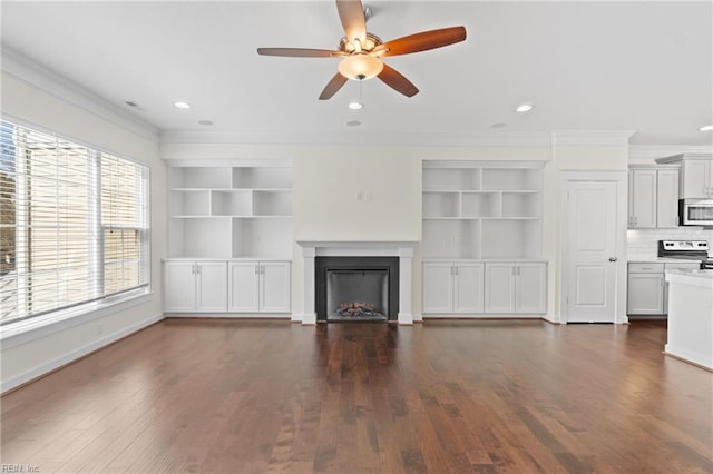 unfurnished living room with ornamental molding, recessed lighting, a warm lit fireplace, and dark wood finished floors