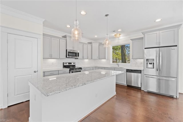 kitchen with a center island, appliances with stainless steel finishes, dark wood-type flooring, ornamental molding, and a sink