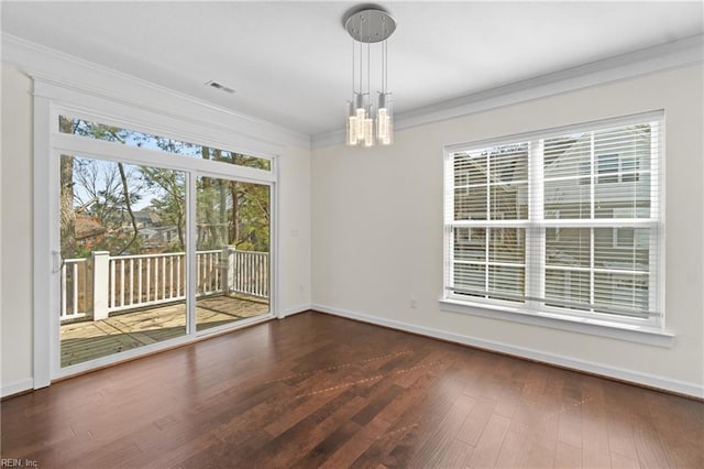 empty room featuring a notable chandelier, baseboards, wood finished floors, and crown molding