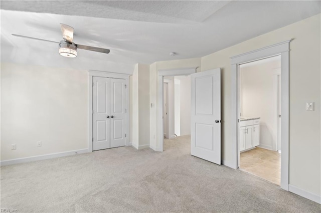 unfurnished bedroom featuring light carpet, ceiling fan, baseboards, and a closet