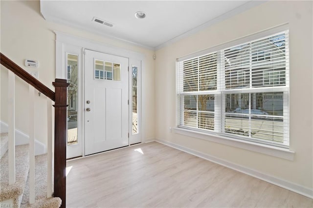 entrance foyer featuring a healthy amount of sunlight, stairs, ornamental molding, and wood finished floors