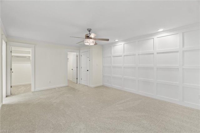 unfurnished bedroom with light carpet, a ceiling fan, a walk in closet, a decorative wall, and recessed lighting