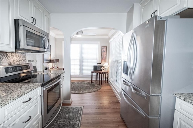 kitchen featuring light stone counters, white cabinets, appliances with stainless steel finishes, tasteful backsplash, and dark wood finished floors