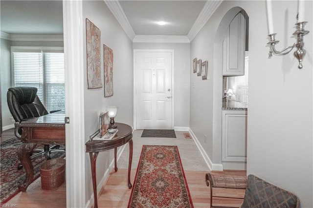 entryway featuring arched walkways, ornamental molding, light wood-type flooring, and baseboards