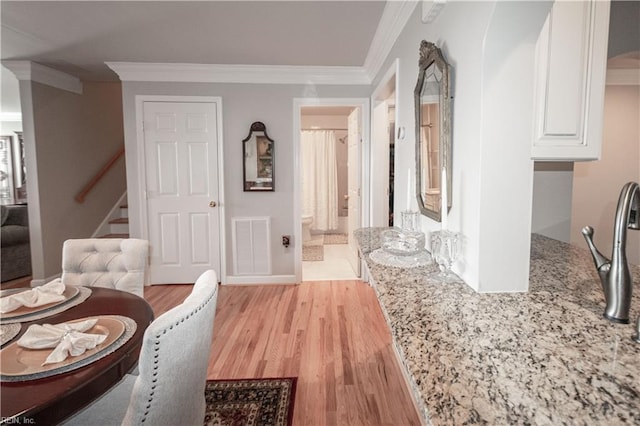 dining space featuring visible vents, crown molding, light wood finished floors, and stairs