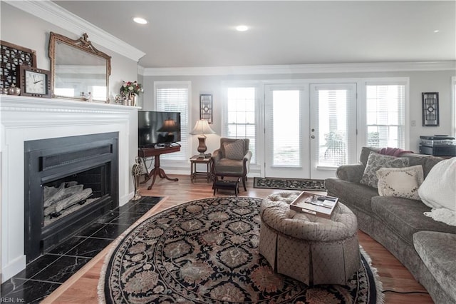 living area featuring a fireplace with flush hearth, french doors, crown molding, and recessed lighting
