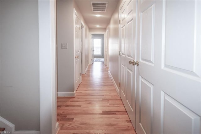 hallway featuring light wood-style floors, visible vents, and baseboards