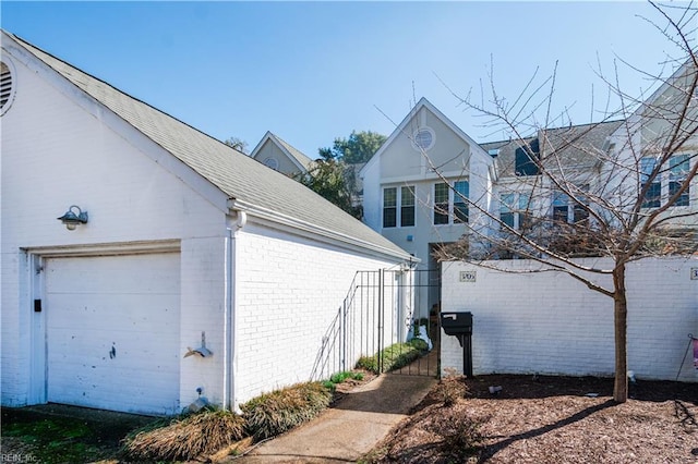 view of property exterior with a garage, an outdoor structure, and brick siding
