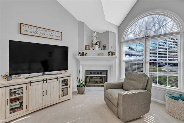 carpeted living area with lofted ceiling, a glass covered fireplace, and baseboards