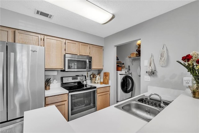 kitchen featuring stainless steel appliances, washer / clothes dryer, light countertops, and a sink