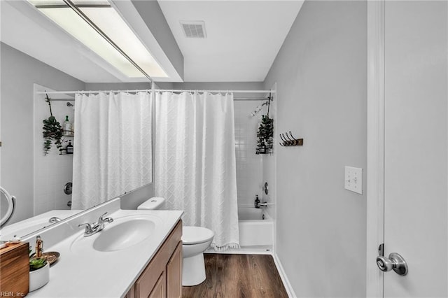 bathroom with toilet, wood finished floors, vanity, visible vents, and shower / bath combination with curtain