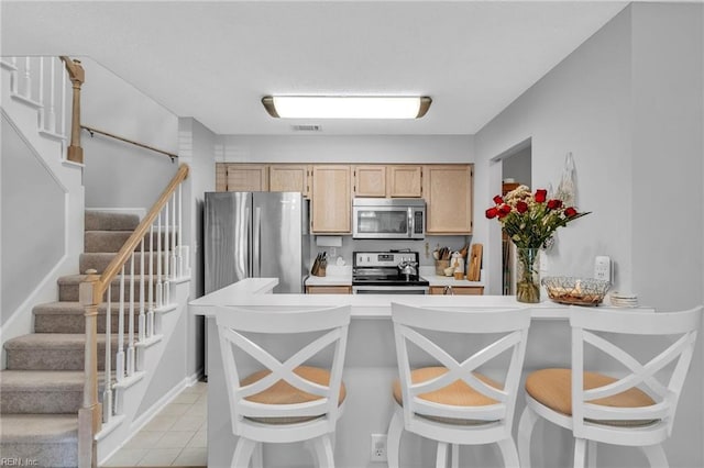 kitchen with light tile patterned floors, visible vents, stainless steel appliances, light countertops, and light brown cabinetry