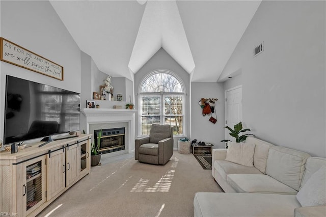 living area with high vaulted ceiling, a fireplace with flush hearth, visible vents, and light colored carpet