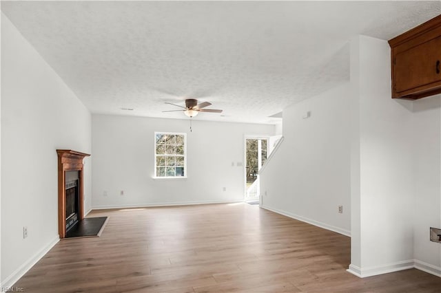 unfurnished living room featuring a fireplace with flush hearth, light wood-style flooring, and a textured ceiling