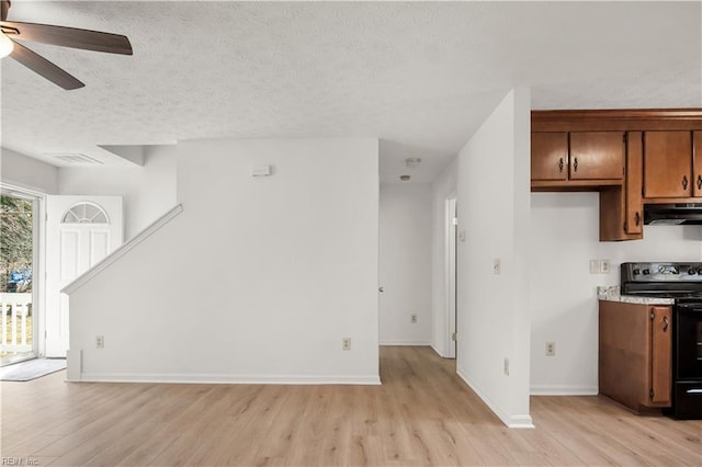 interior space with light wood-style flooring, baseboards, ceiling fan, and a textured ceiling