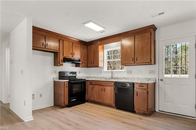 kitchen with visible vents, brown cabinetry, under cabinet range hood, light countertops, and black appliances