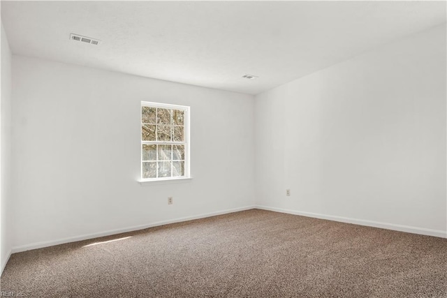 carpeted spare room with visible vents and baseboards