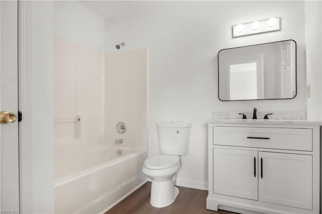 full bath with bathtub / shower combination, toilet, vanity, wood finished floors, and baseboards