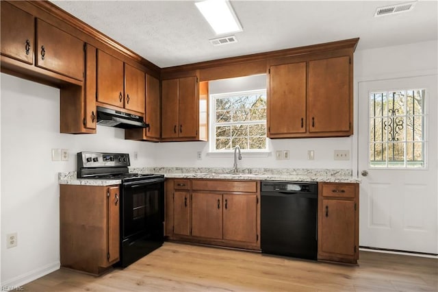 kitchen with black appliances, under cabinet range hood, visible vents, and a sink