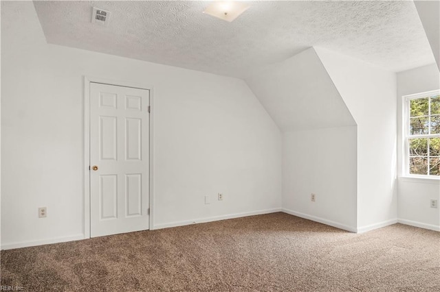 bonus room with baseboards, visible vents, vaulted ceiling, a textured ceiling, and carpet floors