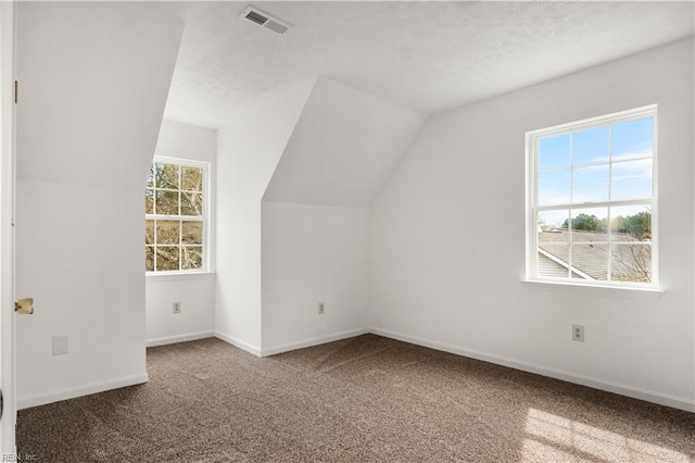 bonus room featuring visible vents, carpet flooring, vaulted ceiling, a textured ceiling, and baseboards