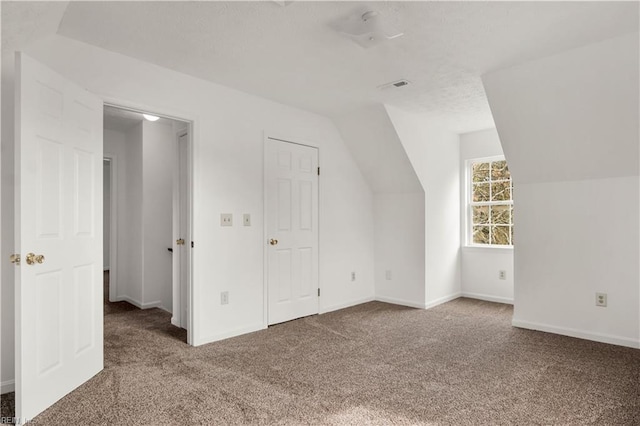 additional living space with carpet floors, baseboards, visible vents, and lofted ceiling